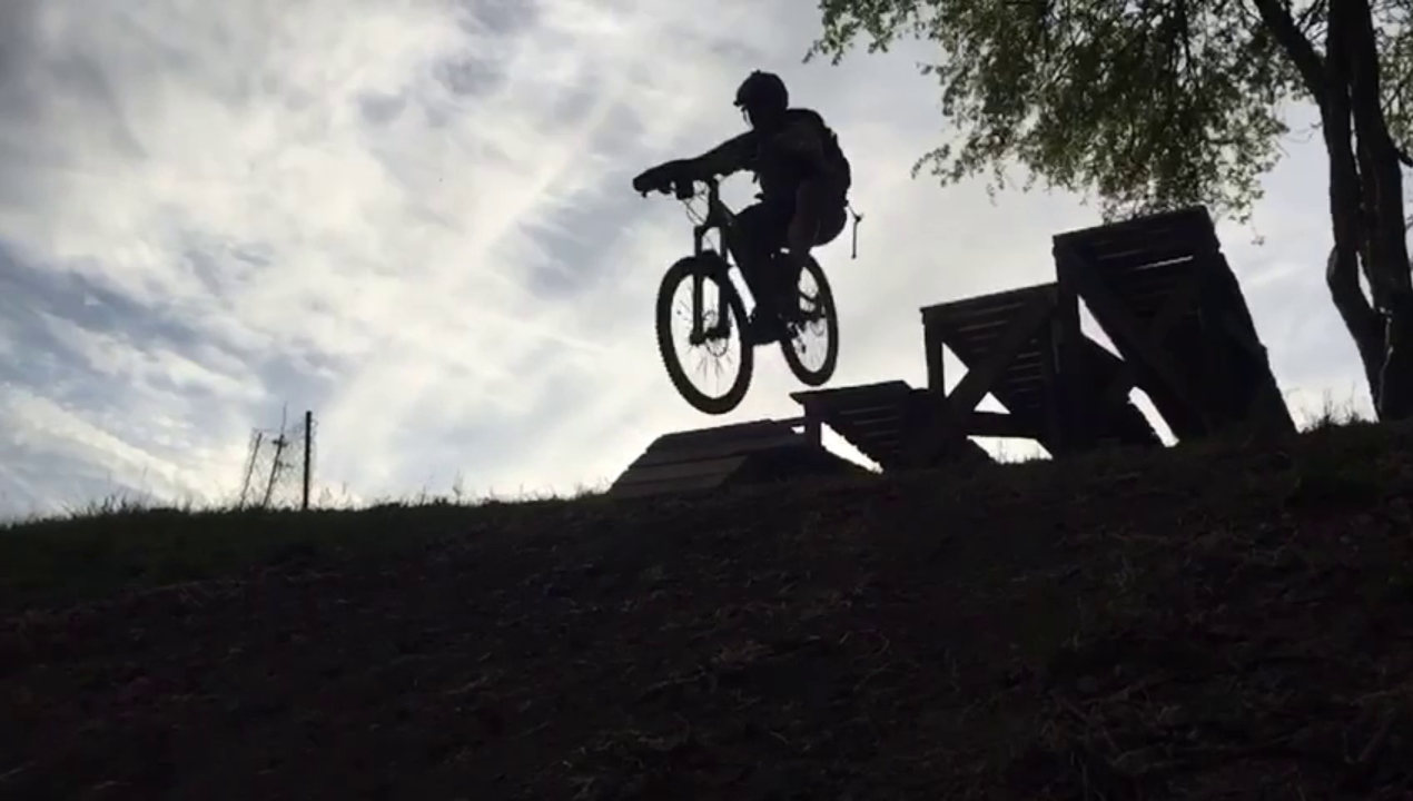 Mountainbiker beim Sprung über eine Holzrampe